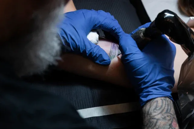 A close-up photo of a tattoo artist in gloves